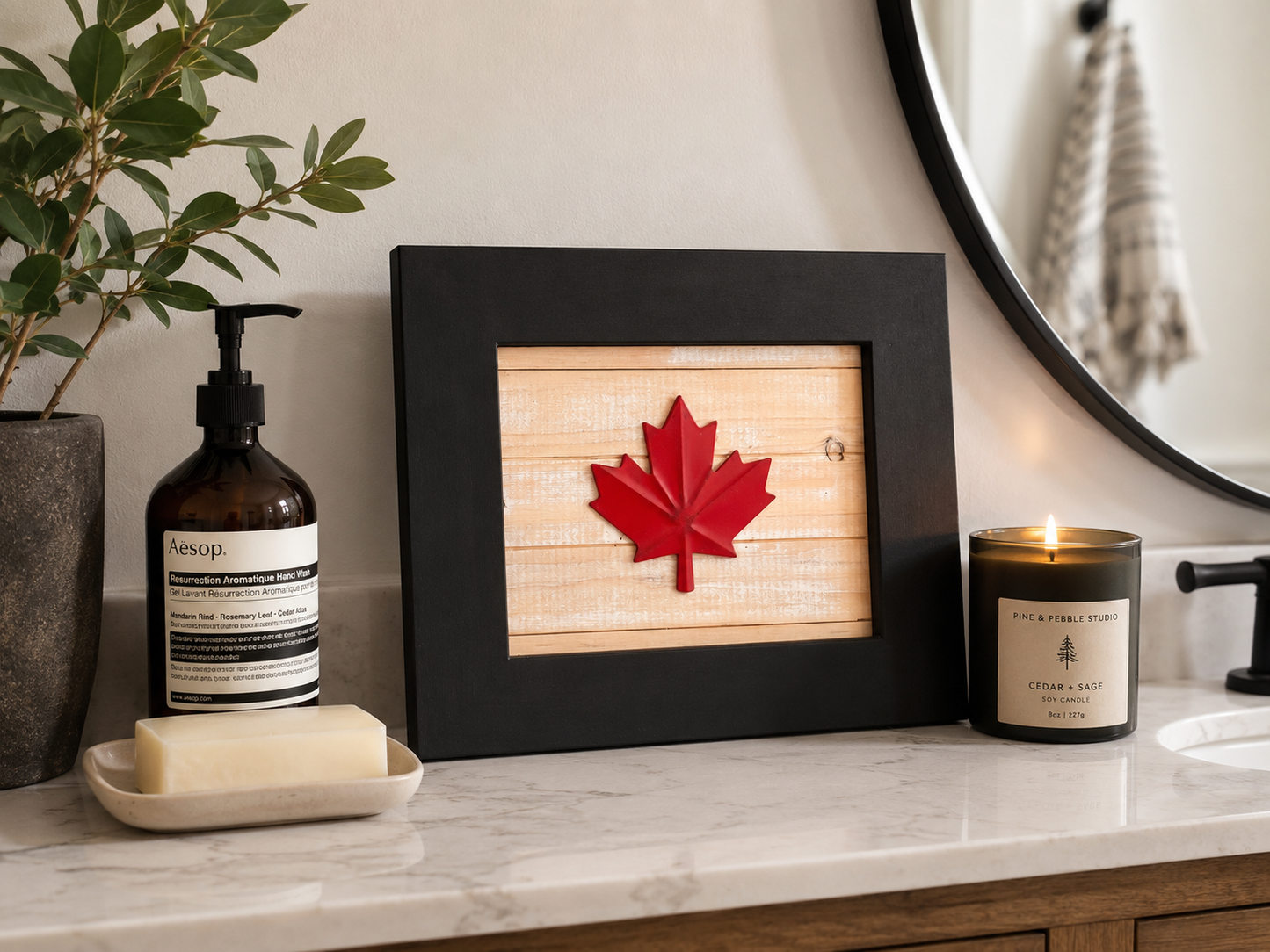 Reclaimed wood Canadian maple leaf wall art with black frame, styled on a marble bathroom vanity alongside an Aesop hand wash and a Pine and Pebble Studio Cedar and Sage soy candle