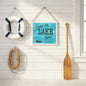 Livin on Lake Time sign hanging in sunny boathouse with vintage paddle life preserver and summer cottage atmosphere